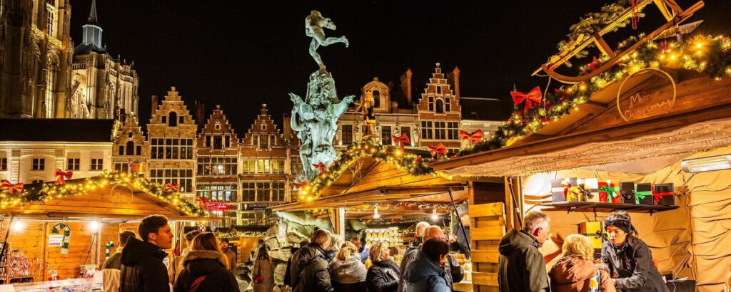 Top 10 Kindvriendelijke Kerstmarkten in Belgiƫ 75 Night scene of Antwerp Christmas Market in Belgium featuring beautifully decorated wooden stalls, festive lights, and historic Gothic architecture in the city square with visitors enjoying holiday shopping and seasonal treats.