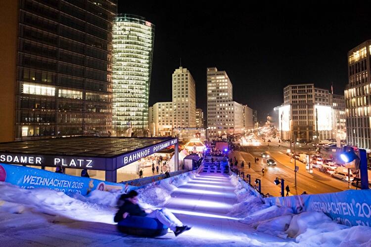 Experience the excitement of Berlin’s Christmas Market at Potsdamer Platz featuring the illuminated Winterwelt sledding hill surrounded by sparkling city skyscrapers. This lively winter scene captures family fun, twinkling lights, and the unique holiday spirit in the heart of Berlin.