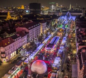 Top 10 Kindvriendelijke Kerstmarkten in Belgiƫ 87 Aerial nighttime view of Brussels Christmas Market in Belgium, featuring rows of festive stalls, sparkling holiday lights, crowds of shoppers, and vibrant cityscape in the heart of Winter Wonders celebrations.