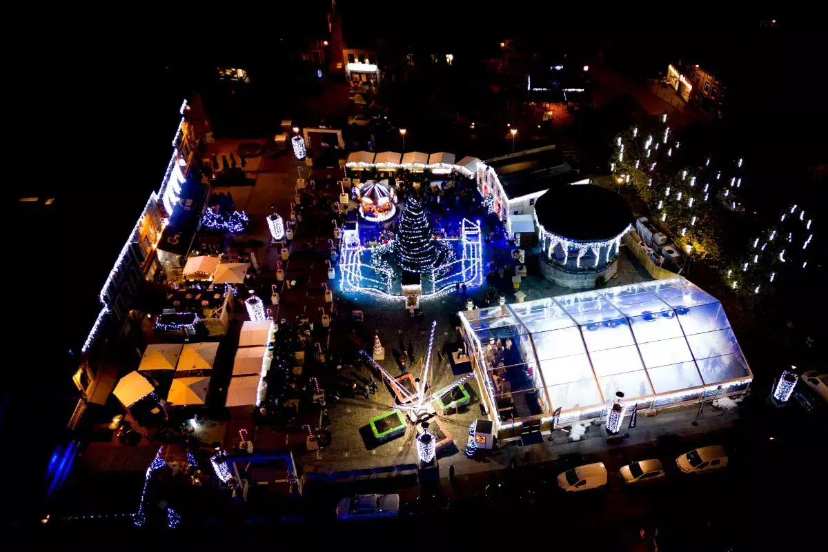 Top 10 Kindvriendelijke Kerstmarkten in Belgiƫ 72 Aerial night view of Ciney Christmas Market in Germany showcasing illuminated Christmas trees, decorated market stalls, light displays, and cheerful visitors enjoying winter festivities from above.