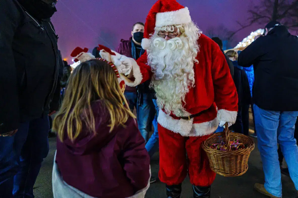 Top 10 Kindvriendelijke Kerstmarkten in Belgiƫ 74 Santa Claus in bright red costume handing out candy to a child at Ciney Christmas Market in Germany, surrounded by festive visitors and joyful holiday atmosphere.