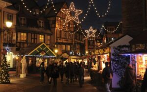 Colmar Christmas Market illuminated at dusk with a glowing Christmas tree, festive holiday stalls, and families enjoying the magical evening atmosphere. Perfect for winter travel and family-friendly holiday experiences in Alsace, France.