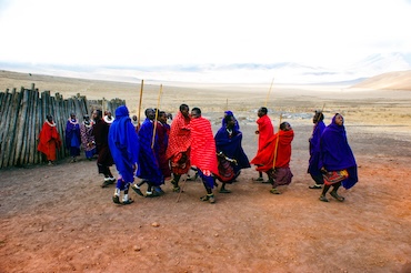 Maasai krijgers in traditionele kleding dansen in hun dorp nabij de Ngorongoro Krater in Tanzania – kleurrijke culturele ontmoeting tijdens een reis met kinderen.