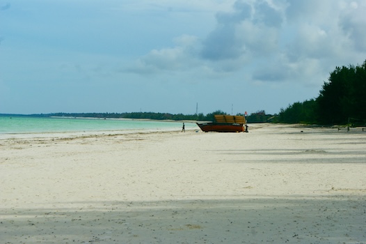 Rustig wit zandstrand met houten boot op Zanzibar, Tanzania – tropisch strandtafereel tijdens een gezinsreis.