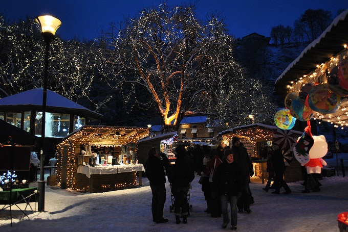 Top 10 Kindvriendelijke Kerstmarkten in Belgiƫ 104 Magical evening at Durbuy Christmas Market in Belgium, with snow-covered ground, sparkling fairy lights wrapped around trees, and cozy illuminated wooden stalls welcoming visitors to a winter wonderland.