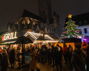 Top 10 Kindvriendelijke Kerstmarkten in Belgiƫ 79 People gathered at Ghent Christmas Market in Belgium, enjoying food at a festive illuminated grill stall, with a decorated Christmas tree and stunning Gothic cathedral in the background during a lively holiday night.