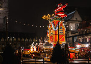 Top 10 Kindvriendelijke Kerstmarkten in Belgiƫ 78 Festive Santa Claus-themed ride illuminated at night during Ghent Christmas Market in Belgium, with decorated holiday stalls, joyful visitors, and historic city buildings in the vibrant winter atmosphere.