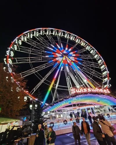 Top 10 Kindvriendelijke Kerstmarkten in Belgiƫ 93 Spectacular illuminated Swisswheel Ferris wheel with colorful lights at Hasselt Christmas Market in Belgium, as visitors enjoy the festive Winterland atmosphere and family fun at night.