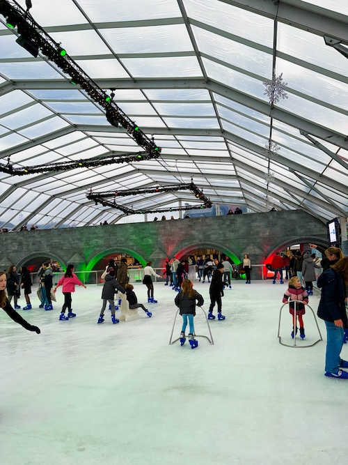 Families and children enjoying ice skating on the festive rink at Maastricht Magical Christmas Market in Vrijthof Square. Covered ice rink with holiday lights and lively atmosphere, perfect for winter activities and family-friendly Christmas celebrations in the Netherlands.