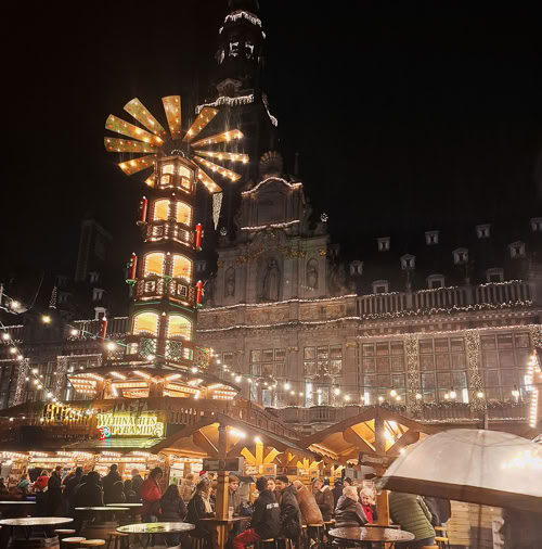 Top 10 Kindvriendelijke Kerstmarkten in Belgiƫ 97 Leuven Christmas Market in Belgium glows with warm holiday lights, charming wooden stalls, joyful crowds, and stunning Gothic architecture from the iconic 15th-century Town Hall, creating a cozy festive atmosphere in the city center.