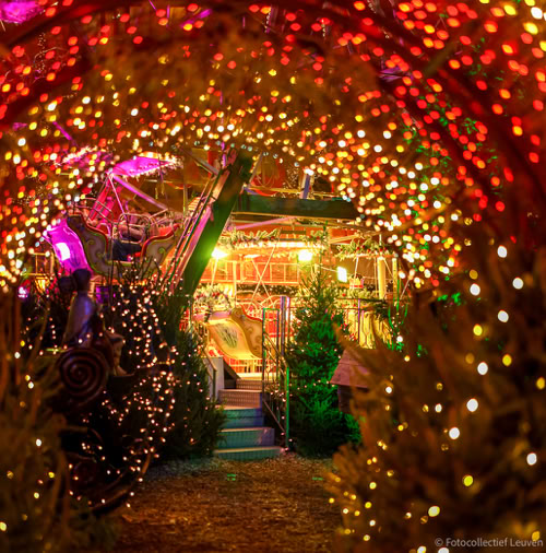 Top 10 Kindvriendelijke Kerstmarkten in Belgiƫ 98 View through a glowing tunnel of Christmas lights towards colorful fairground rides at Leuven Christmas Market in Belgium, creating an enchanting and festive holiday scene.