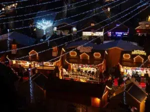 Top 10 Best Child-Friendly Christmas Markets in France 98 Cozy decorated chalet stalls illuminated with string lights at Lille Christmas Market. Visitors enjoy shopping for holiday treats and gifts under sparkling blue fairy lights in a magical winter atmosphere in Lille, France.