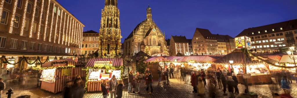 Top 10 Kindvriendelijke Kerstmarkten in Duitsland 35 Discover the magical atmosphere of Nuremberg Christkindlesmarkt in the historic Old Town. This vibrant night scene features beautifully illuminated market stalls, the famous Frauenkirche, and joyful visitors enjoying one of Germany’s oldest and most celebrated Christmas markets.