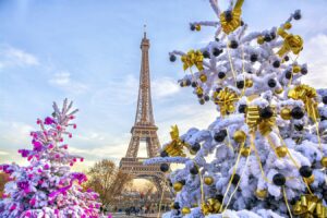 Festive snowy Christmas trees adorned with gold and pink decorations near the Eiffel Tower at Paris Christmas Market, with a clear sky and visitors enjoying the iconic holiday scene. Best for winter travel, family holidays, and magical moments in Paris, France.