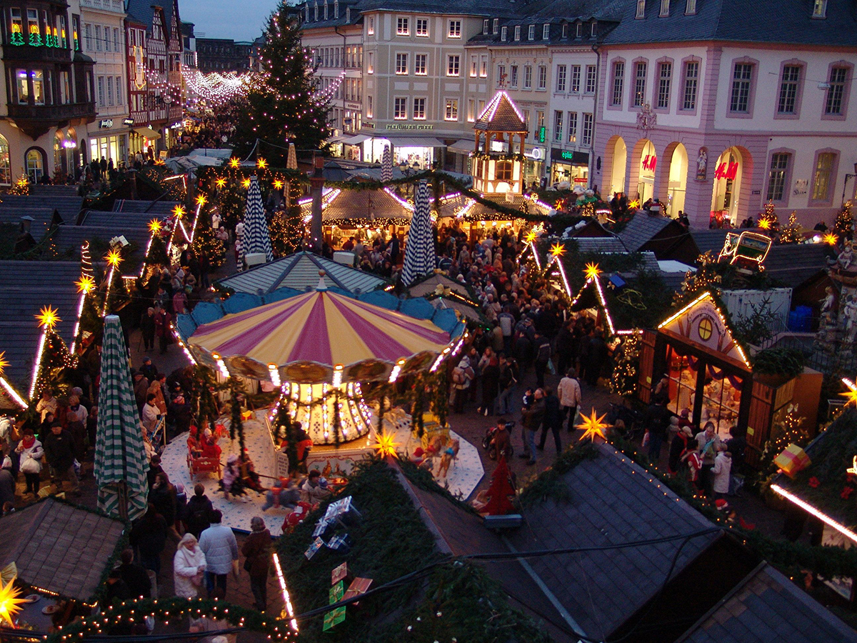 Experience the joyful atmosphere of Trier Christmas Market with its magical carousel, glowing holiday lights, and lively crowds set against the backdrop of historic architecture. This enchanting scene showcases traditional stalls, family fun, and the vibrant spirit of Christmas in Germany’s oldest city.