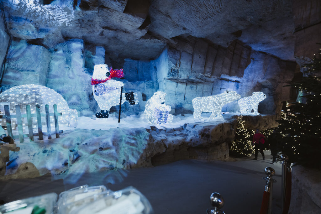 Illuminated polar bear and igloo decorations inside Valkenburg’s Municipality Cave (Gemeentegrot) Christmas Market in the Netherlands. Unique underground holiday experience featuring sparkling festive lights and wintry family displays beneath historic caves.