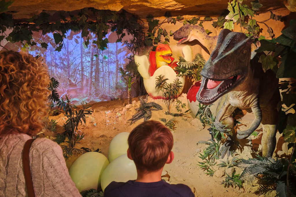 Family and children explore lifelike dinosaur sculptures and interactive displays in DinoRijk inside Valkenburg’s Mergelrijk Caves during the Christmas Markets. Unique underground attraction in the Netherlands featuring fun holiday activities for kids and families.