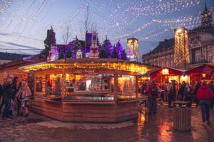Festive wooden chalet stalls at Liege Christmas Market in Belgium glow under twinkling strings of lights, as visitors enjoy holiday shopping and the magical winter atmosphere in the city center