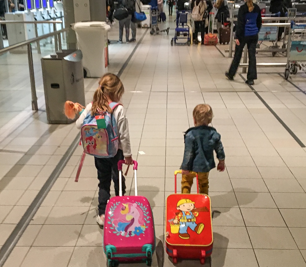 Kinderen lopen zelfstandig met hun koffers door de luchthaven tijdens een gezinsreis
